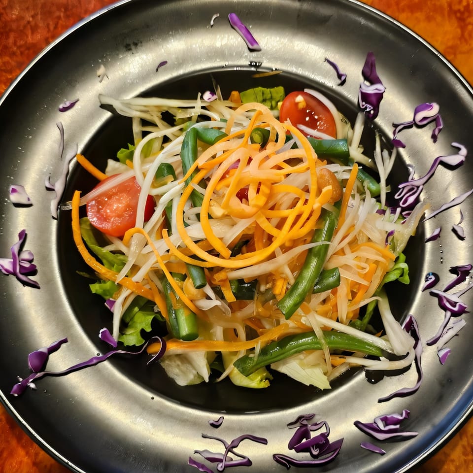 Colorful Thai salad with shredded carrots, green beans, and tomatoes on a dark plate.